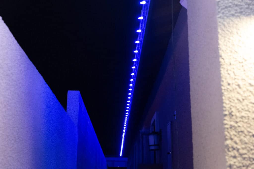 Blue custom Christmas lights installed along a roofline edge