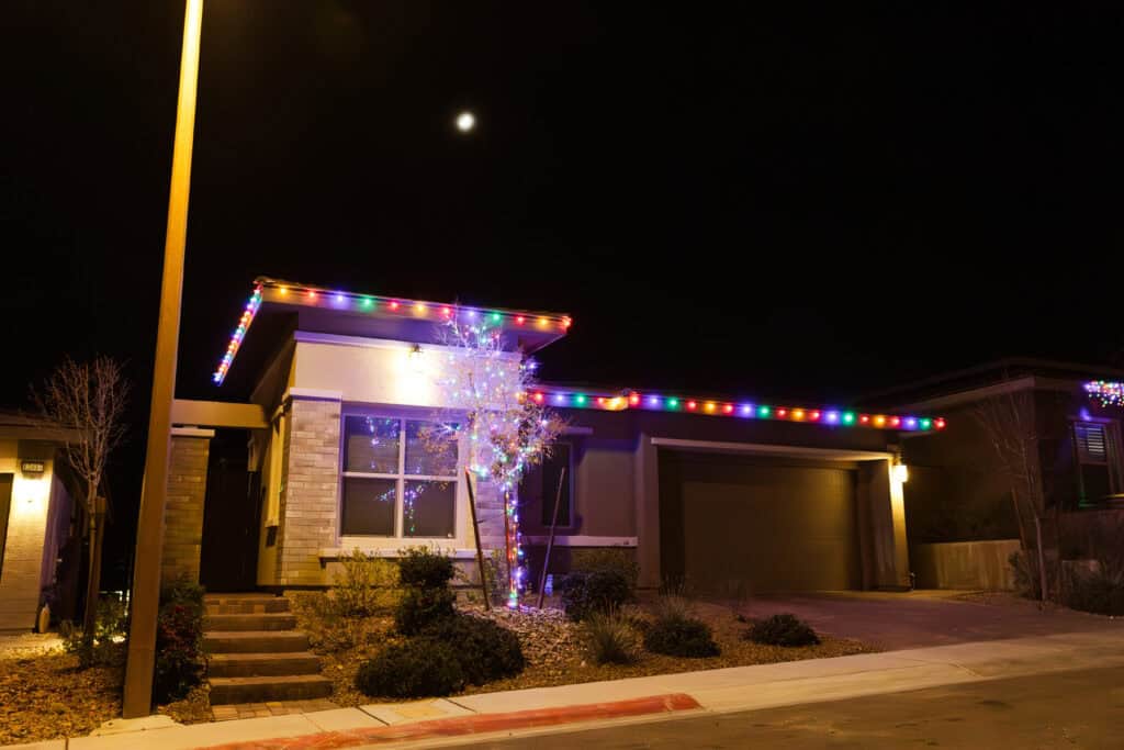 Multi-colored Christmas Lights Installed on tile roof and tree in front yard of house in las vegas