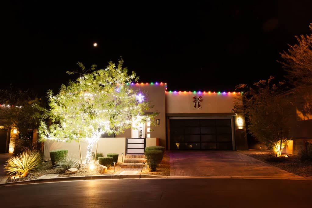 Multi-colored Christmas Lights Installed on tile roof and tree decorated with white christmas lights