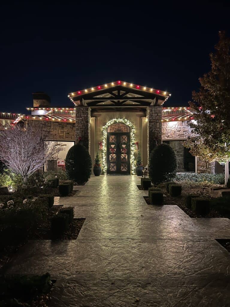 Warm White and Red Candy Cane Christmas Lights installed over stone entryway, custom lit garland over the front door of a ranch style home in Las Vegas