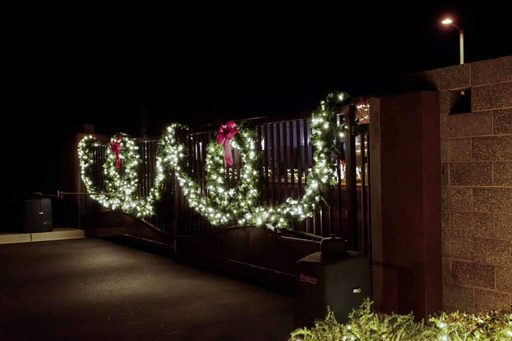 Warm white lighted garland swags on a private gate entrance