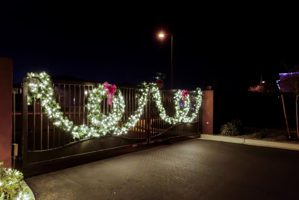 Warm white garland and red bows on a community entry gate