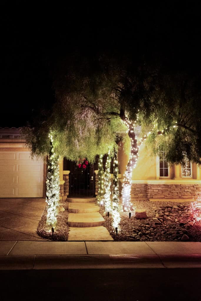 Warm white Christmas lights wrapping columns at a home entrance