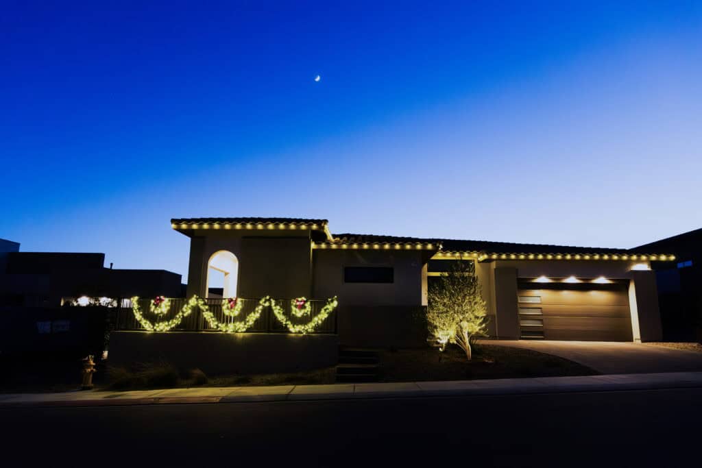 Warm white roofline Christmas lights and garland at twilight